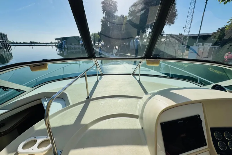 Slide: The Image of 2000 Cruisers Yachts 3575 Express boat cockpit with clear windshield and serene marina view. - 34