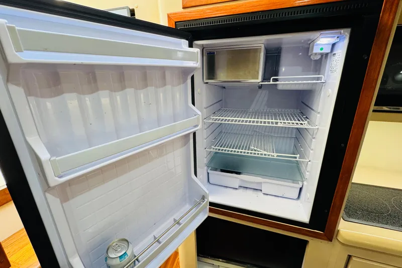 Slide: The Image of Open refrigerator inside 2000 Cruisers Yachts 3575 Express, showing shelves and a beverage can. - 54