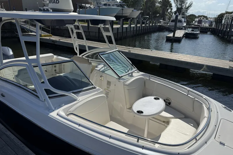 Slide: The Image of 2018 Robalo R247 Dual Console boat docked at marina, featuring spacious seating and table. - 3