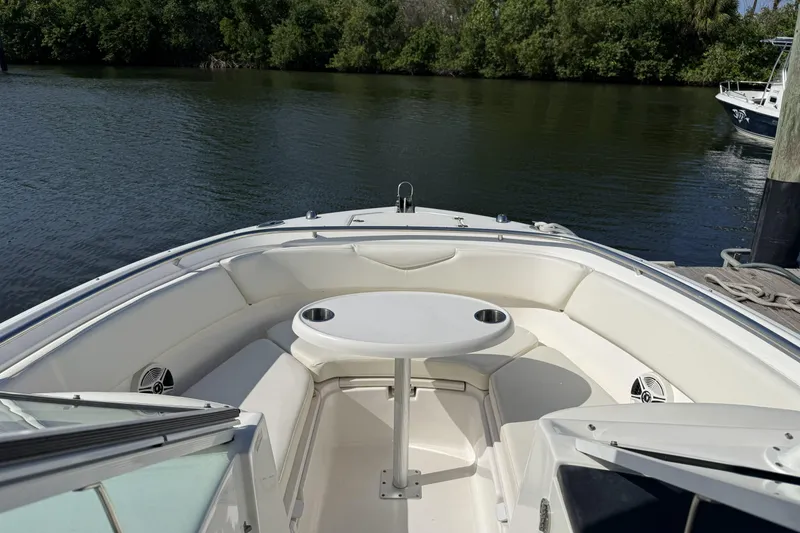 Slide: The Image of 2018 Robalo R247 Dual Console boat interior with seating and table on calm water. - 4