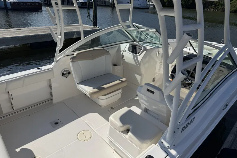 Slide: The Image of 2018 Robalo R247 Dual Console boat interior with seating and steering wheel, docked by the water. - 8