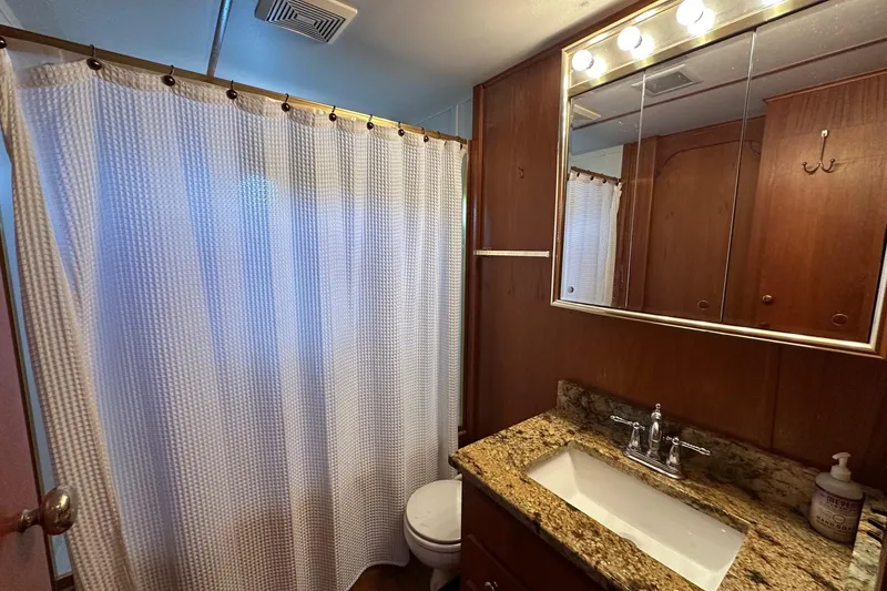 Slide: The Image of 1990 Lazy Days 14x72 bathroom with granite countertop, wooden cabinets, and shower curtain. - 12
