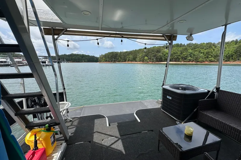 Slide: The Image of Houseboat deck with seating, overlooking serene lake and forested shoreline. Lazy Days 14x72, 1990 model. - 14