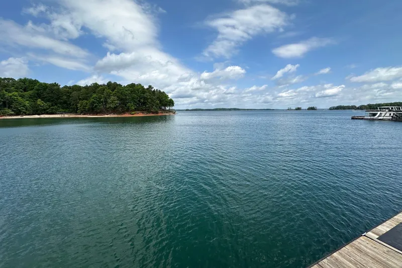 Slide: The Image of Calm lake view with a docked 1990 Lazy Days houseboat under a partly cloudy sky. - 17