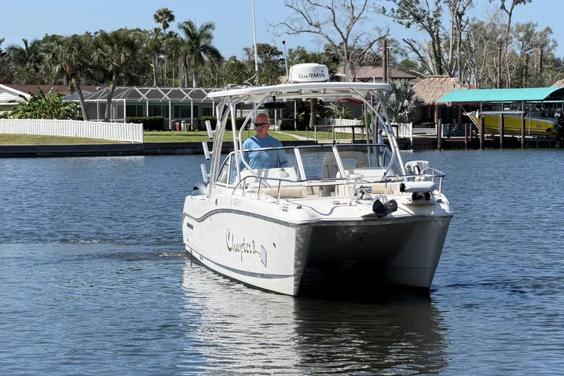 Slide: The Image of 2017 World Cat 255 DC boat cruising on a calm waterway near waterfront homes. - 16
