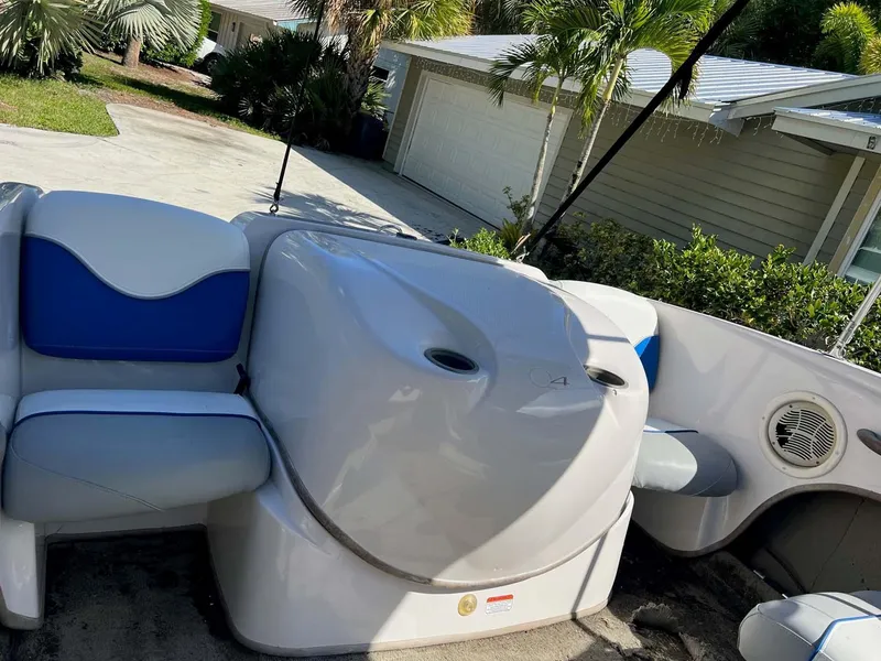 Slide: The Image of 2005 Tahoe T18 Ski Boat interior with blue and white seating, parked near a house. - 14