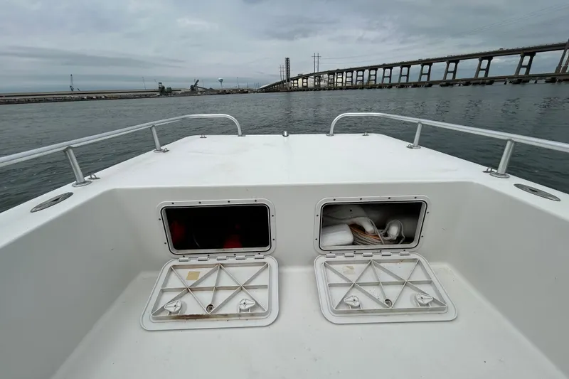 Slide: The Image of KenCraft 2060 boat deck with open storage compartments, 2009 model, near a bridge on a cloudy day. - 15