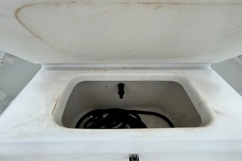 Slide: The Image of Open storage compartment on a 2009 KenCraft 2060 boat, showing interior with coiled hose. - 18