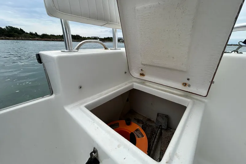 Slide: The Image of Open storage compartment on a 2009 KenCraft 2060 boat, showing interior and nearby water. - 23