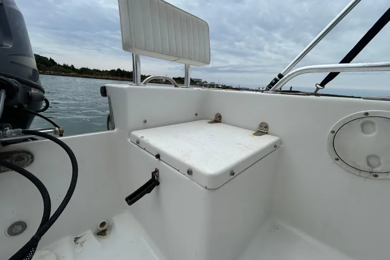 Slide: The Image of 2009 KenCraft 2060 boat interior with seating and storage, on calm water under cloudy sky. - 24