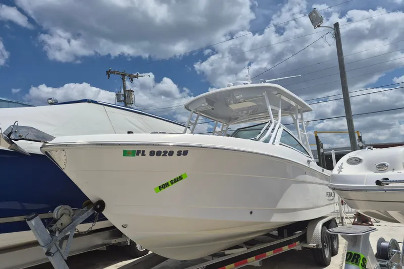 The Image of 2021 Robalo R247 Dual Console boat for sale, parked on trailer under cloudy sky. - 1