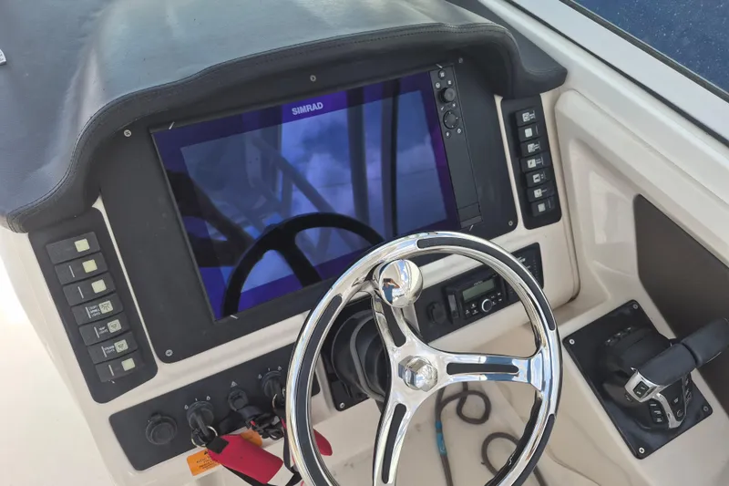 Slide: The Image of 2021 Robalo R247 Dual Console dashboard with steering wheel and Simrad display. - 13