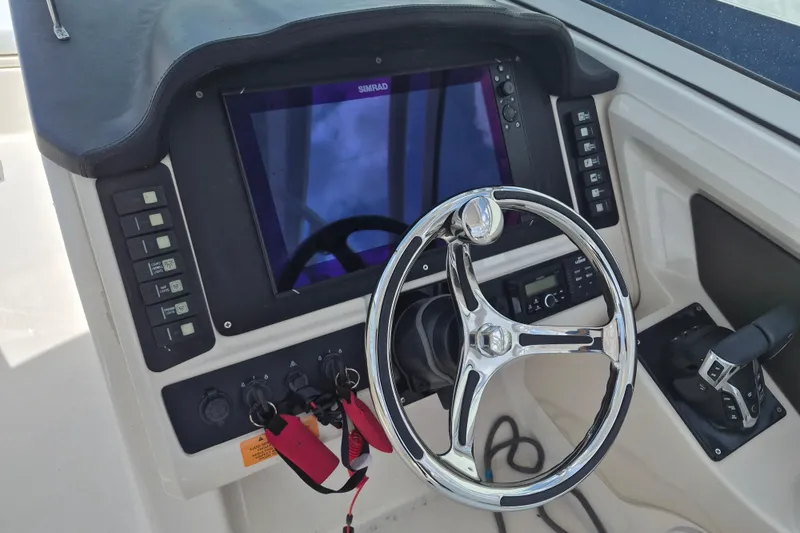 Slide: The Image of 2021 Robalo R247 Dual Console helm with steering wheel, control panel, and Simrad display. - 15