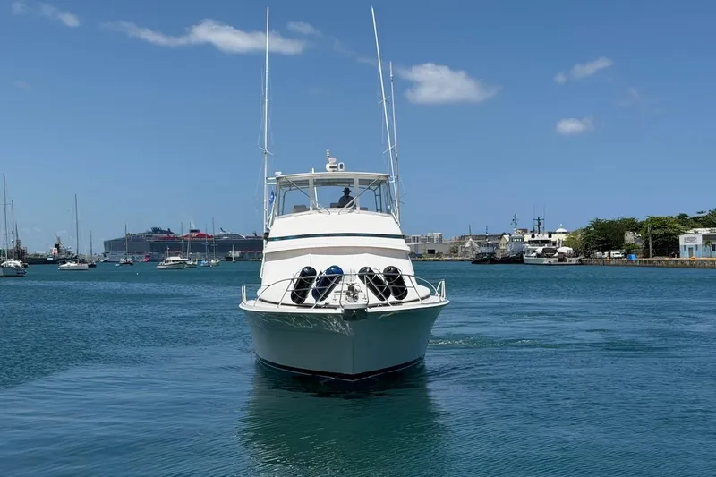 Slide: The Image of 1995 Bertram 60 Convertible yacht cruising in a harbor under a clear blue sky. - 11
