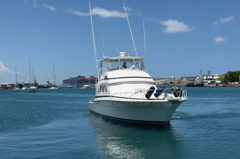 Slide: The Image of 1995 Bertram 60 Convertible yacht cruising in a harbor under a clear blue sky. - 12