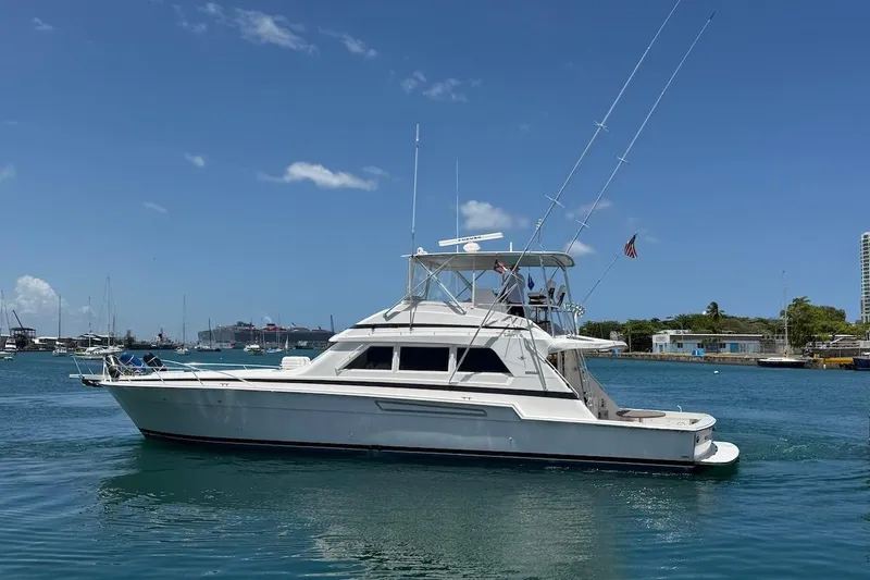Slide: The Image of 1995 Bertram 60 Convertible yacht cruising in a sunny harbor. - 2