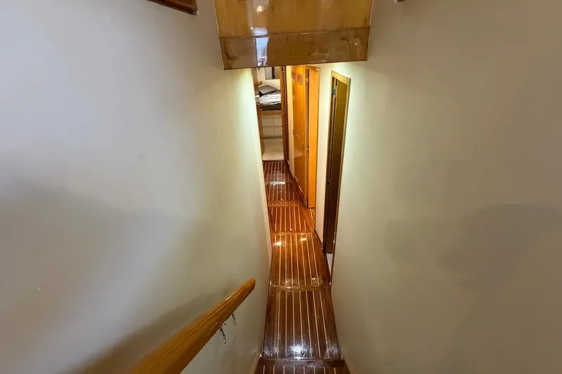 Slide: The Image of Narrow hallway with wooden flooring inside a 1995 Bertram 60 Convertible yacht. - 25