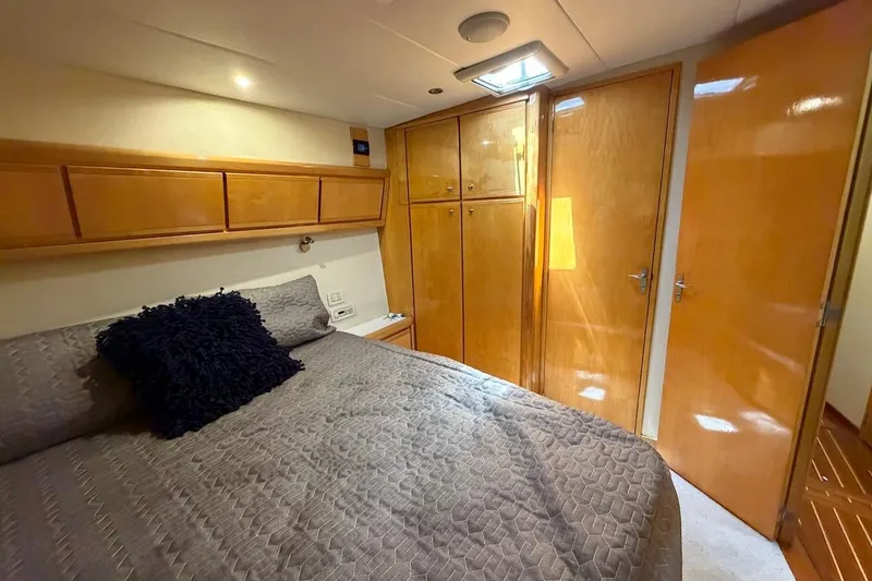 Slide: The Image of Cozy bedroom in a 1995 Bertram 60 Convertible yacht with wooden cabinetry and plush bedding. - 30