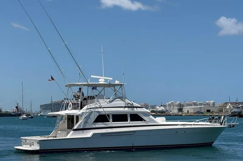 Slide: The Image of 1995 Bertram 60 Convertible yacht cruising in a sunny harbor with clear blue skies. - 7