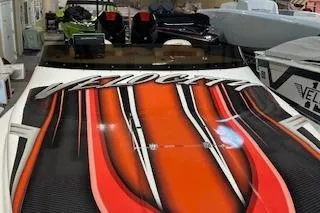 Slide: The Image of 2021 Velocity 290 Sport Cruiser with vibrant orange and black design in showroom. - 8