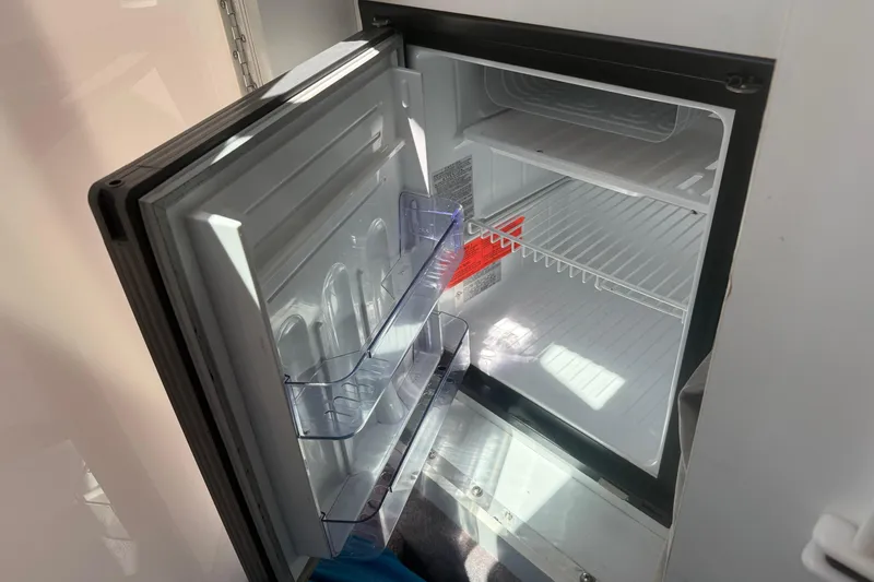 Slide: The Image of Open refrigerator inside a 2001 Formula 353 FASTech boat, showing empty shelves and door compartments. - 29