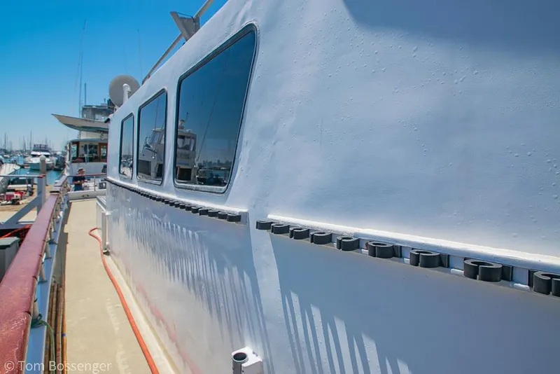 Slide: The Image of 1975 Blanchard Passenger Sportfisher boat docked, showcasing side windows and deck details. - 12