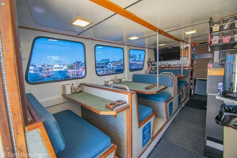 Slide: The Image of Interior of a 1975 Blanchard Passenger Sportfisher with blue seating and large windows. - 48