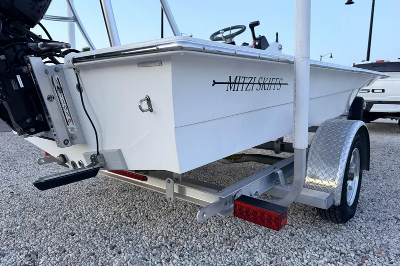 Slide: The Image of 2019 Mitzi Skiffs 17 boat on trailer, rear view, parked on gravel. - 18