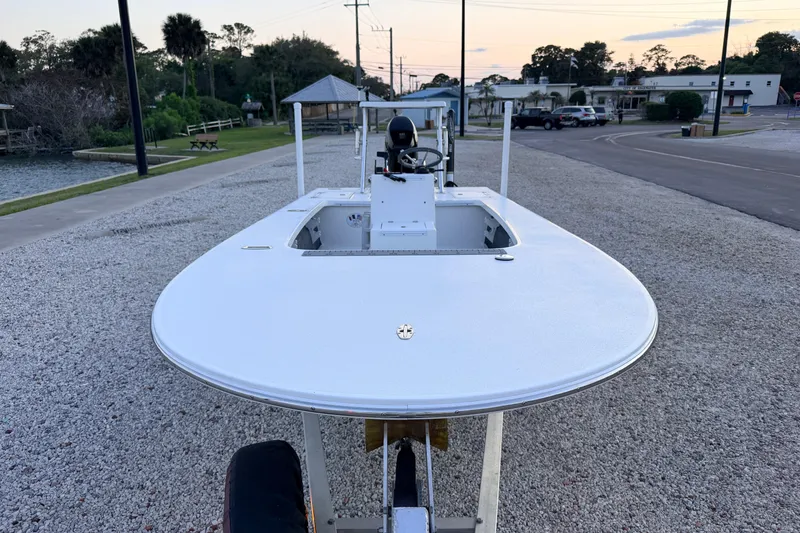 Slide: The Image of 2019 Mitzi Skiffs 17 boat on gravel, near water and trees at sunset. - 3