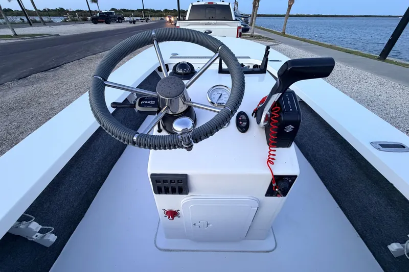 Slide: The Image of 2019 Mitzi Skiffs 17 boat console with steering wheel and controls, parked by the water. - 36