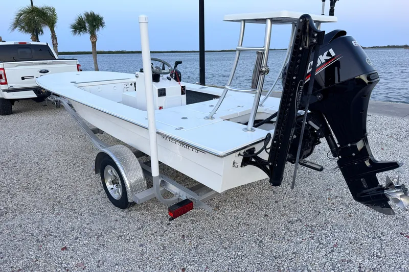 Slide: The Image of 2019 Mitzi Skiffs 17 boat on trailer by waterfront, featuring Suzuki outboard motor. - 9