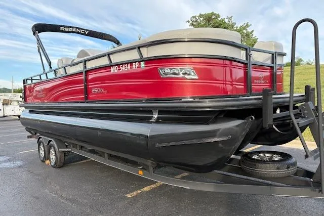 Slide: The Image of 2024 Regency 250 DL3 pontoon boat on trailer, red and black design. - 11