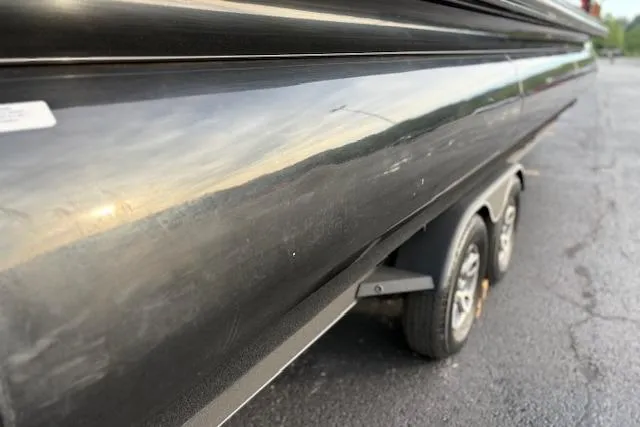 Slide: The Image of 2024 Regency 250 DL3 boat on trailer, close-up view of sleek black hull. - 24
