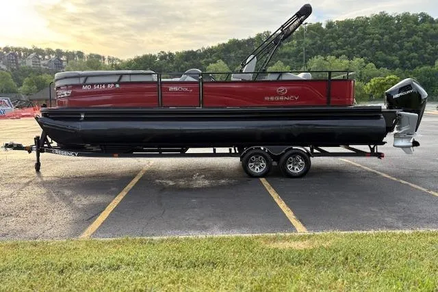 Slide: The Image of 2024 Regency 250 DL3 pontoon boat on trailer in parking lot, surrounded by greenery. - 9