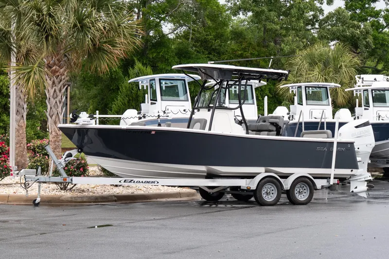 The Image of 2022 Sea Born LX24 Center Console boat on trailer, parked near palm trees. - 1