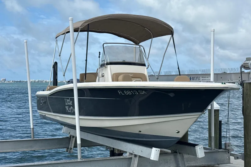The Image of 2021 Scout 195 Sportfish boat on lift by the water, featuring a canopy. - 0