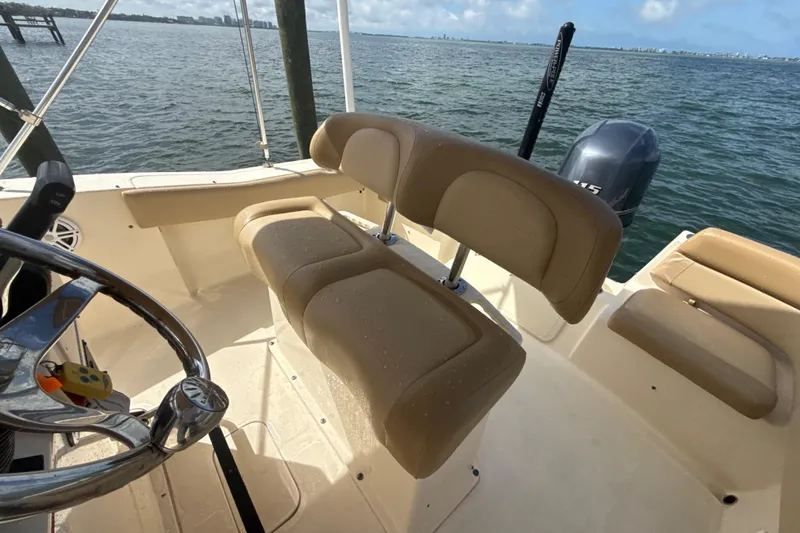 Slide: The Image of 2021 Scout 195 Sportfish boat interior with tan seating and steering wheel, overlooking the water. - 10