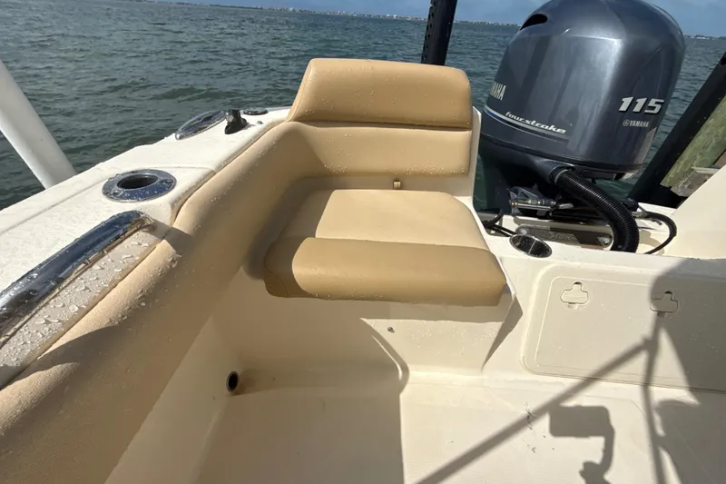 Slide: The Image of 2021 Scout 195 Sportfish boat interior with Yamaha 115 engine, beige seating, and ocean backdrop. - 12