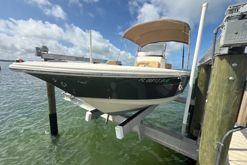 Slide: The Image of 2021 Scout 195 Sportfish boat on lift, docked by the water under a clear sky. - 15