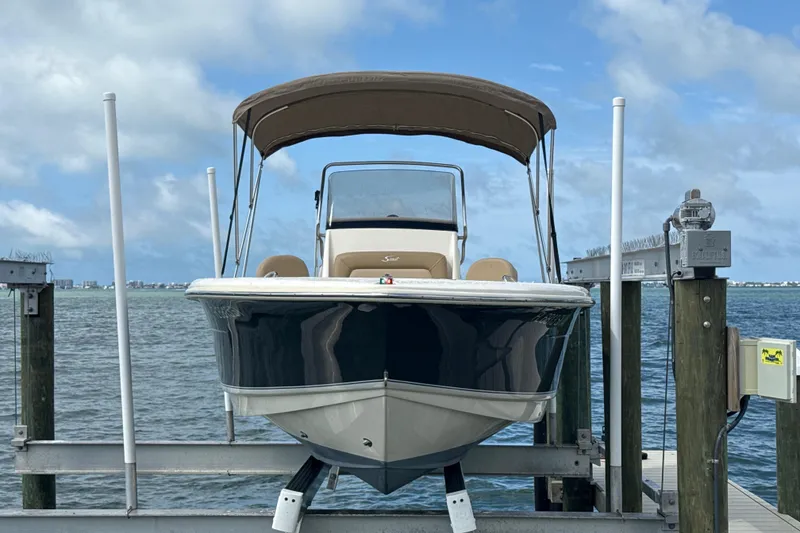 Slide: The Image of 2021 Scout 195 Sportfish boat docked with canopy, ocean view in background. - 16