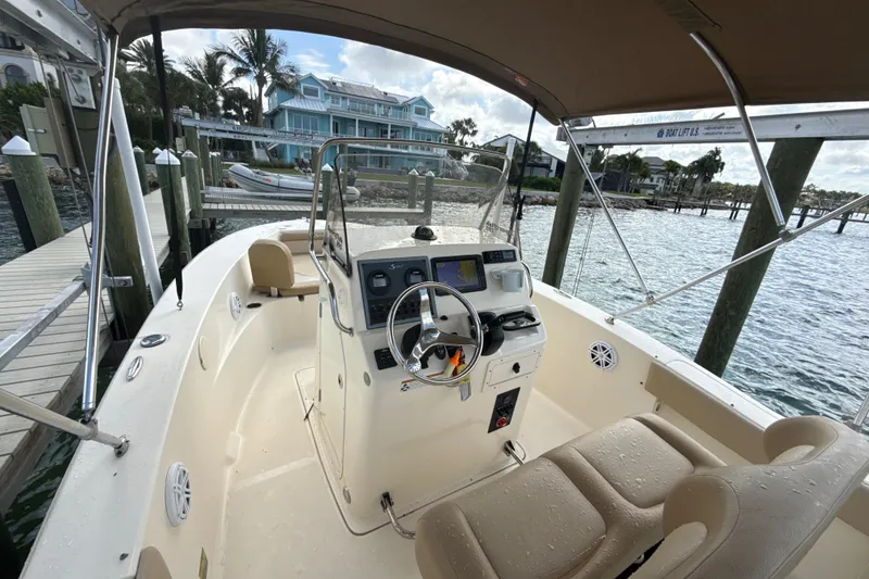 Slide: The Image of 2021 Scout 195 Sportfish boat docked, featuring a spacious helm and comfortable seating. - 2
