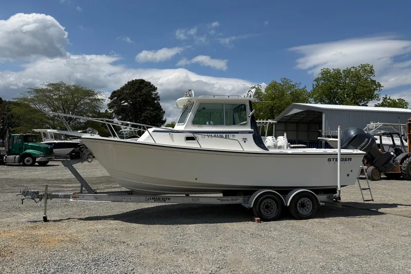 Slide: The Image of 2013 Steiger Craft 23 Miami boat on trailer, parked outdoors under a partly cloudy sky. - 2