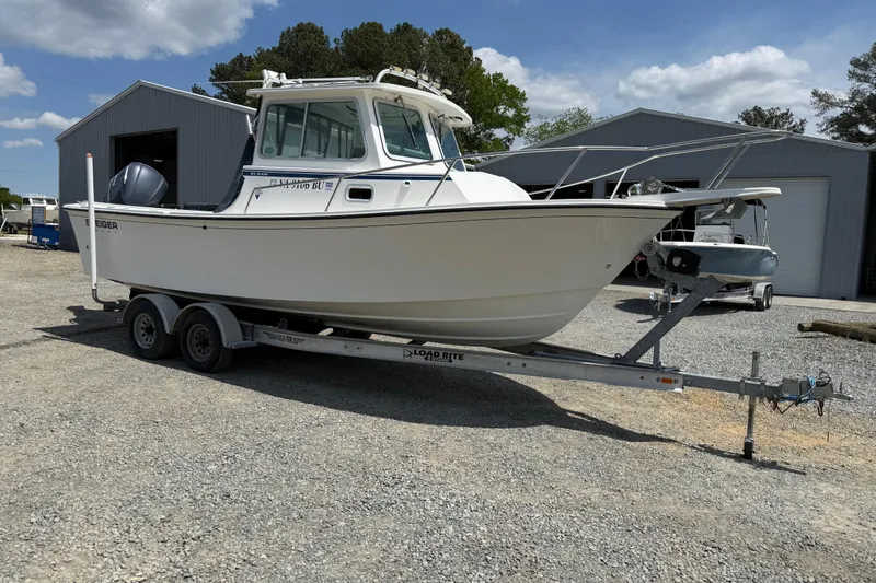 Slide: The Image of 2013 Steiger Craft 23 Miami boat on trailer, parked outside metal buildings. - 21