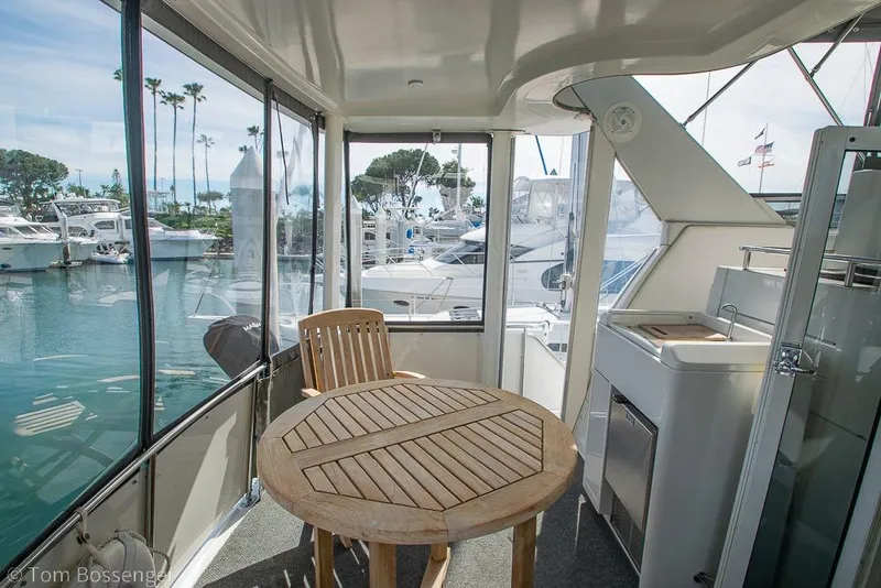 Slide: The Image of 1996 Carver 370 Aft Cabin Motor Yacht interior with wooden table and marina view. - 35