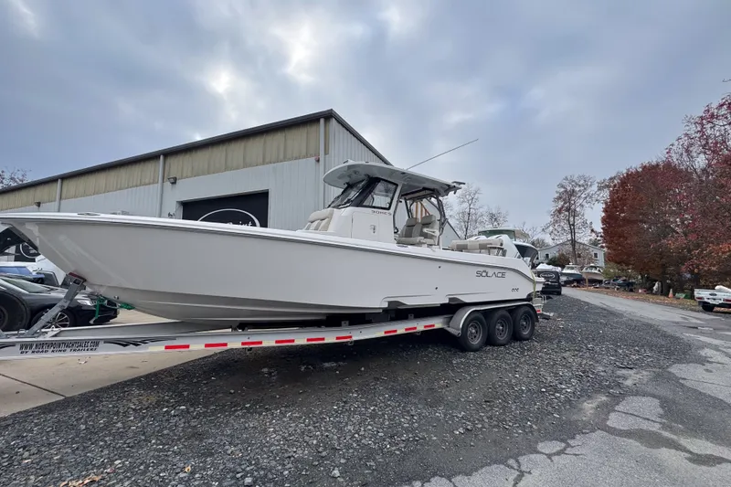 Slide: The Image of 2025 Solace 30 HCS boat on trailer outside a warehouse, under cloudy sky. - 4