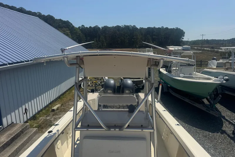 Slide: The Image of 1999 May-Craft 2500 boat with dual engines, parked outdoors near a blue-roofed building. - 13