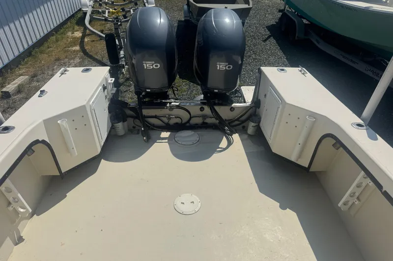 Slide: The Image of 1999 May-Craft 2500 boat with dual Yamaha 150 engines, docked on gravel. - 16