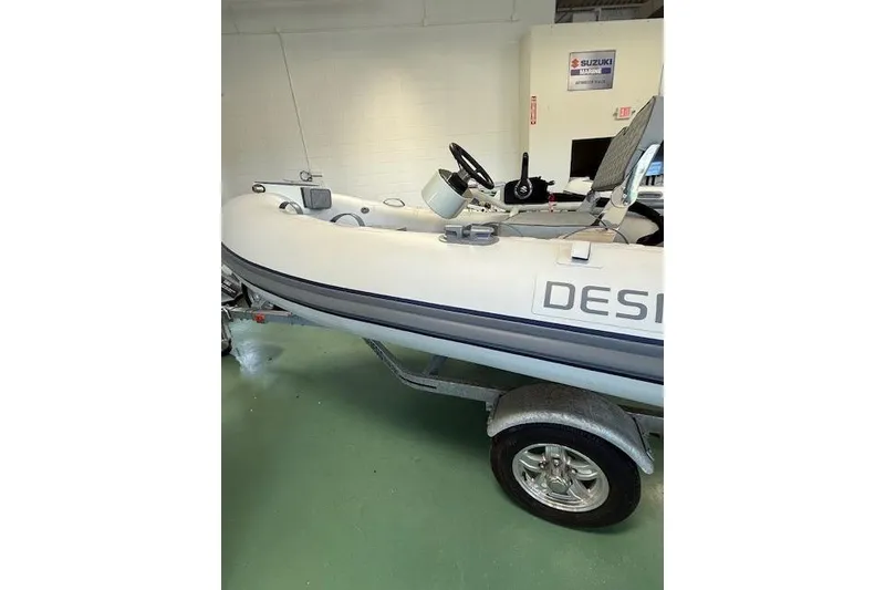 The Image of 2026 Desner Classic 310 FCT inflatable boat on trailer in showroom. - 1