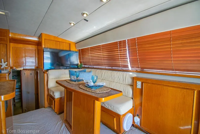 Slide: The Image of Interior of a 1989 Bertram 50 Convertible yacht with dining area and wooden blinds. - 11