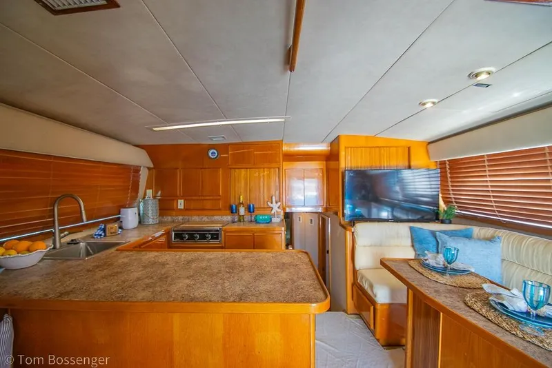Slide: The Image of Luxurious interior of a 1989 Bertram 50 Convertible yacht with modern kitchen and dining area. - 12
